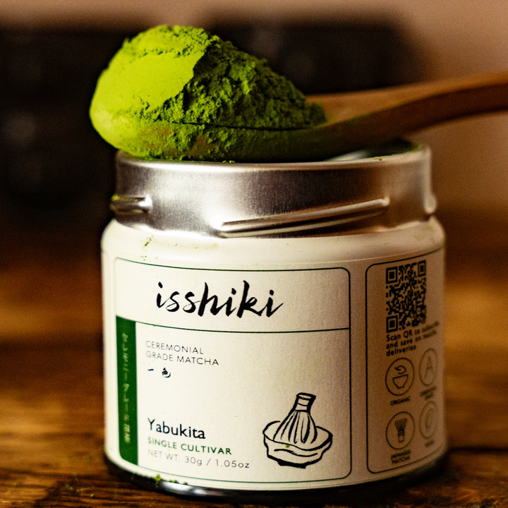 Ceremonial matcha tin with green matcha powder on a wooden spoon
