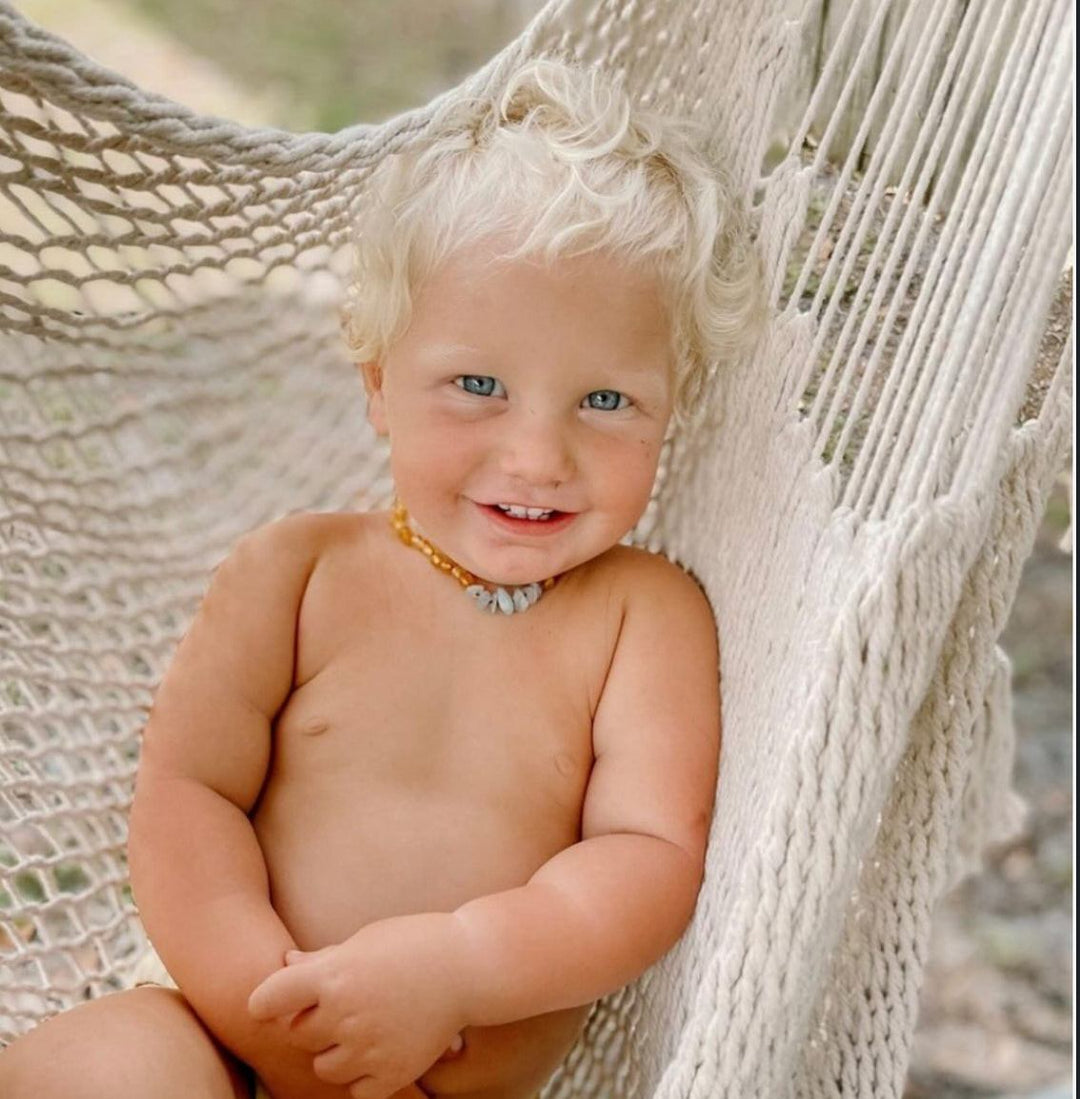 Child wearing amber-brown bead necklace with light blue stone accents