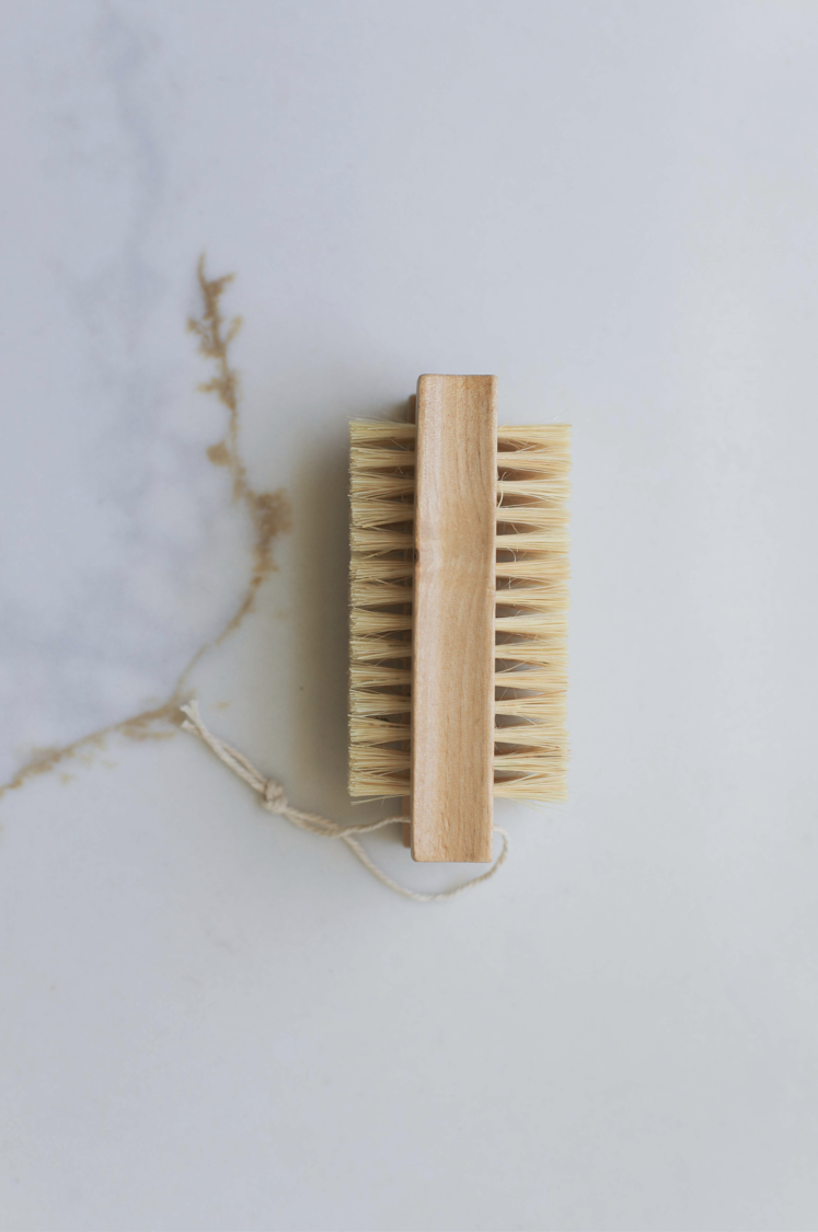 Double-sided nail brush with wooden handle and tan bristles on both sides