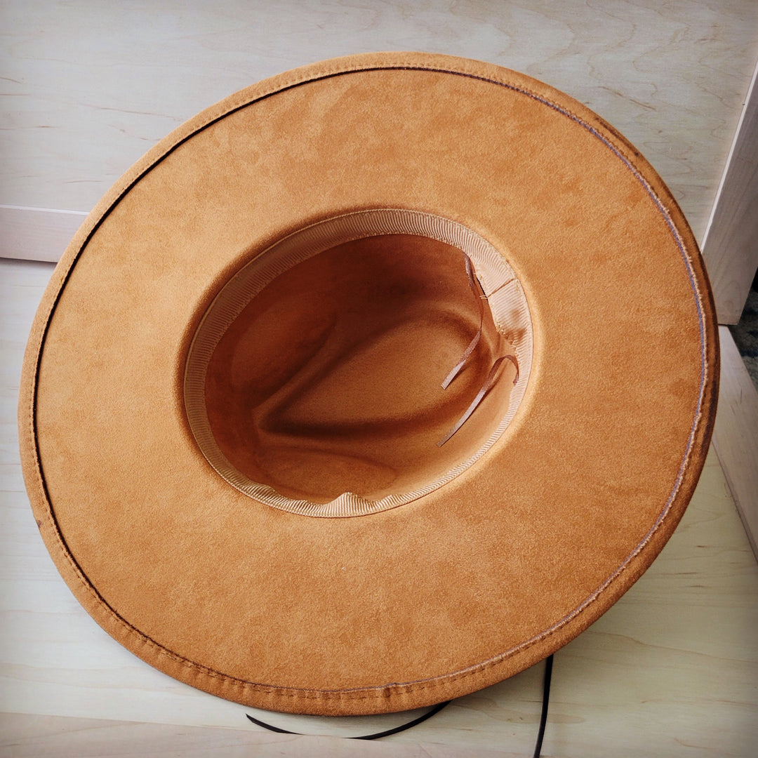 Tan suede-like cowboy hat with curved brim and stitched underside view