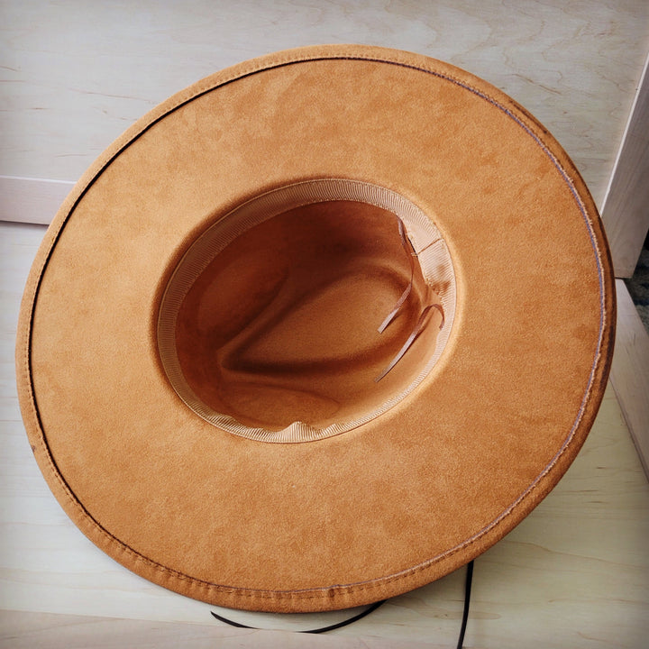 Tan suede-like cowboy hat with curved brim and stitched underside view
