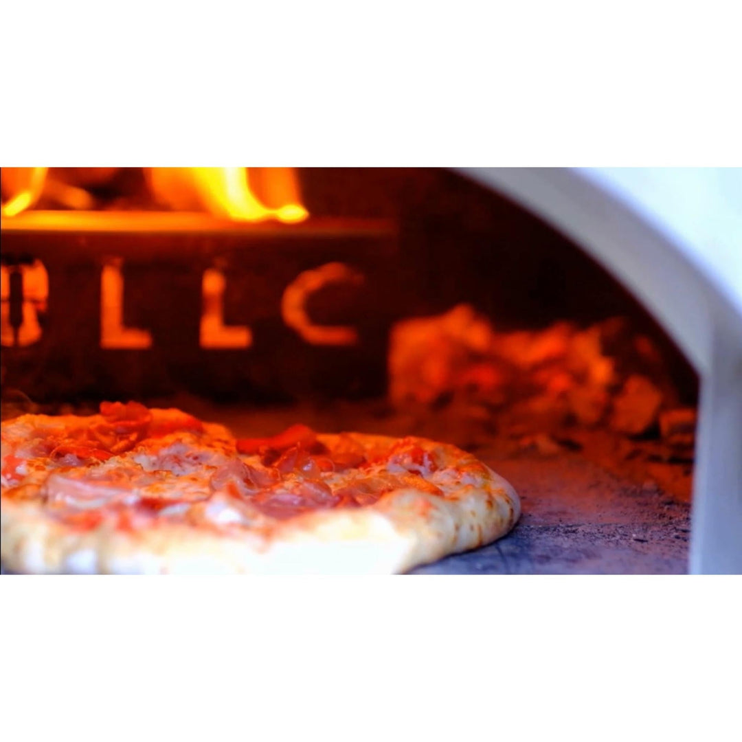 Wood-fired oven interior with pizza baking near the front opening and coals