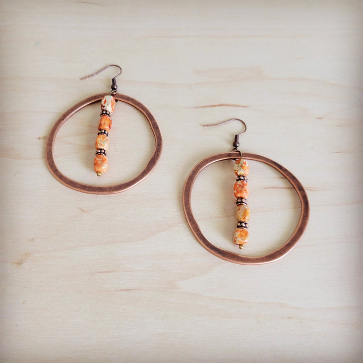 Copper hoop earrings with vertical orange bead dangle and hook backs.