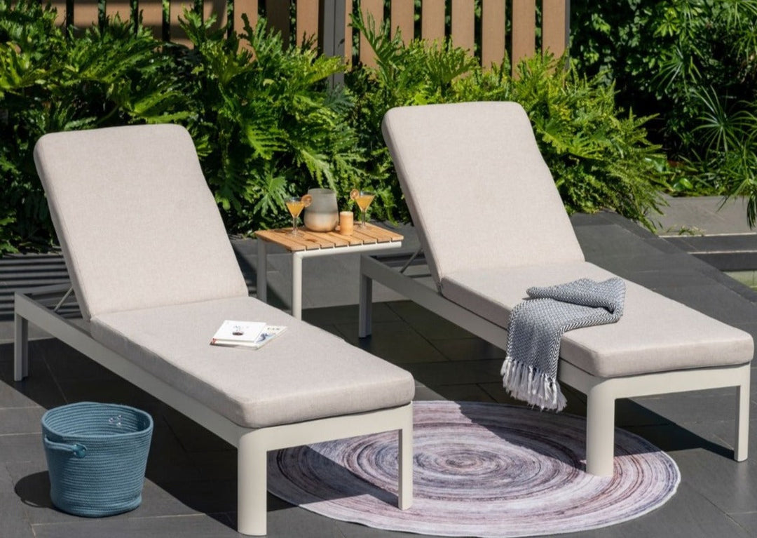 Pair of light beige outdoor sun loungers with padded cushions and adjustable backrests