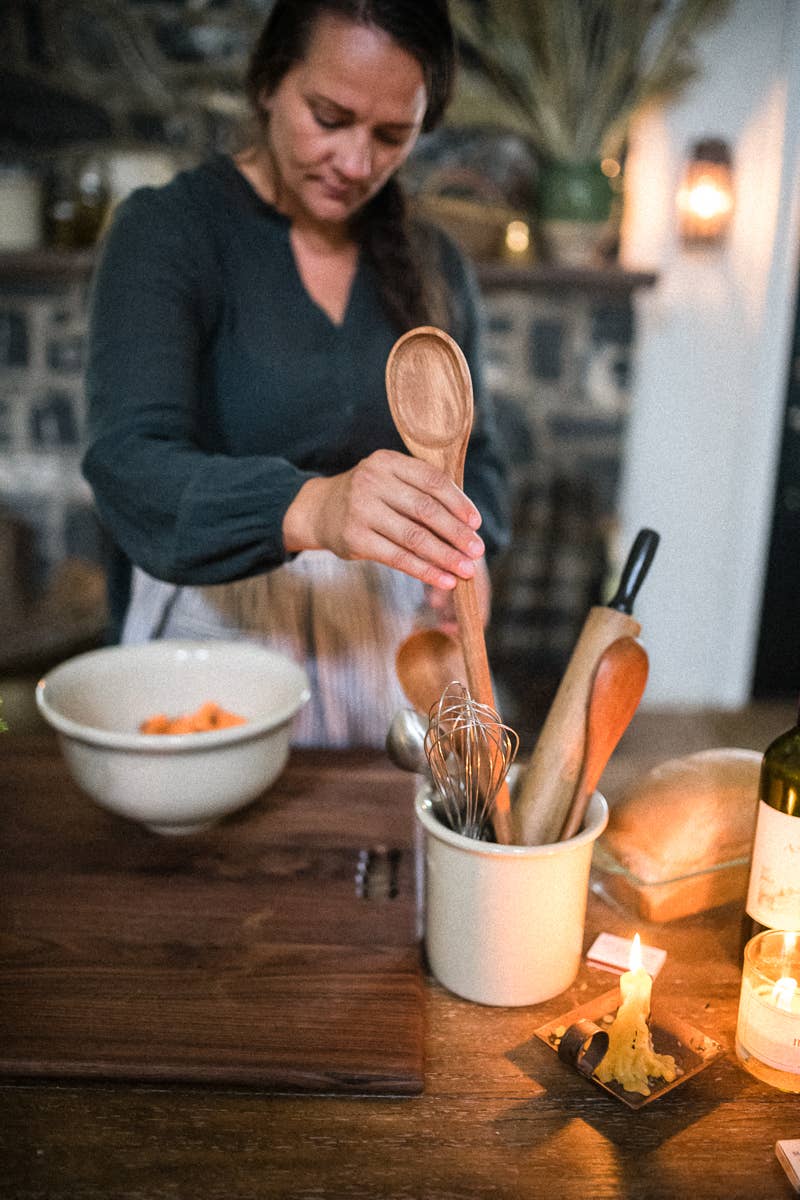 Wooden spoon being held, oval bowl and long handle in light wood grain