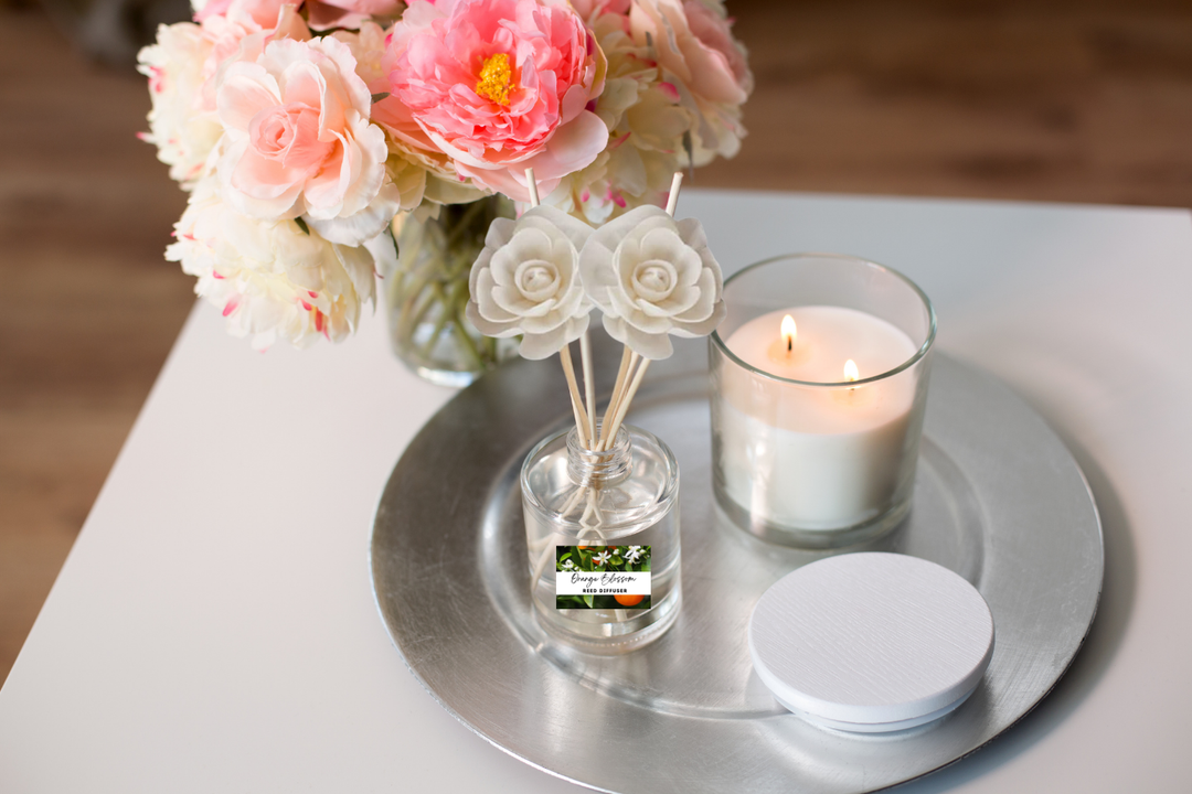 Clear reed diffuser bottle with rose-tipped reeds on a round tray