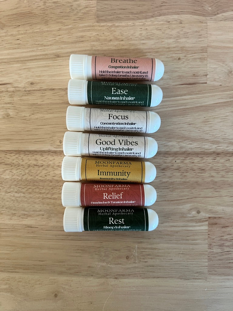 Set of labeled aromatherapy inhaler tubes, assorted blends arranged on wood surface.