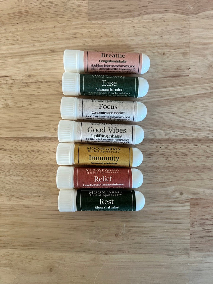 Set of labeled aromatherapy inhaler tubes, assorted blends arranged on wood surface.
