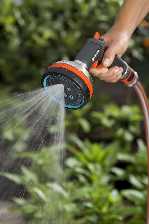 Handheld garden hose sprayer spraying water from blue-and-orange head