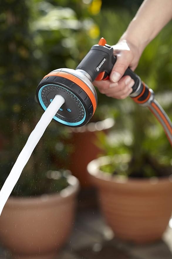 Handheld garden hose sprayer with white water stream from blue-and-orange head
