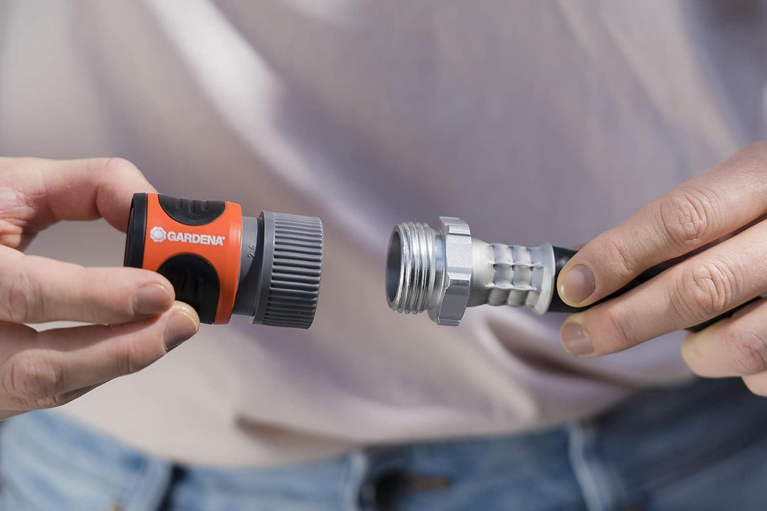 Garden hose connector being attached to a metal coupling, held by hands