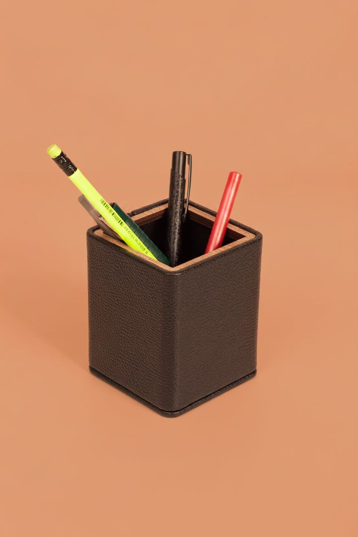 Square black wooden pencil holder with textured sides and open top filled with pencils