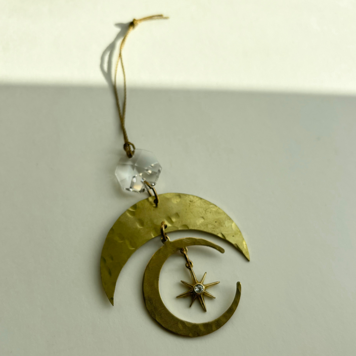Gold crescent-moon ornament with clear faceted crystal and star charm, hanging on string