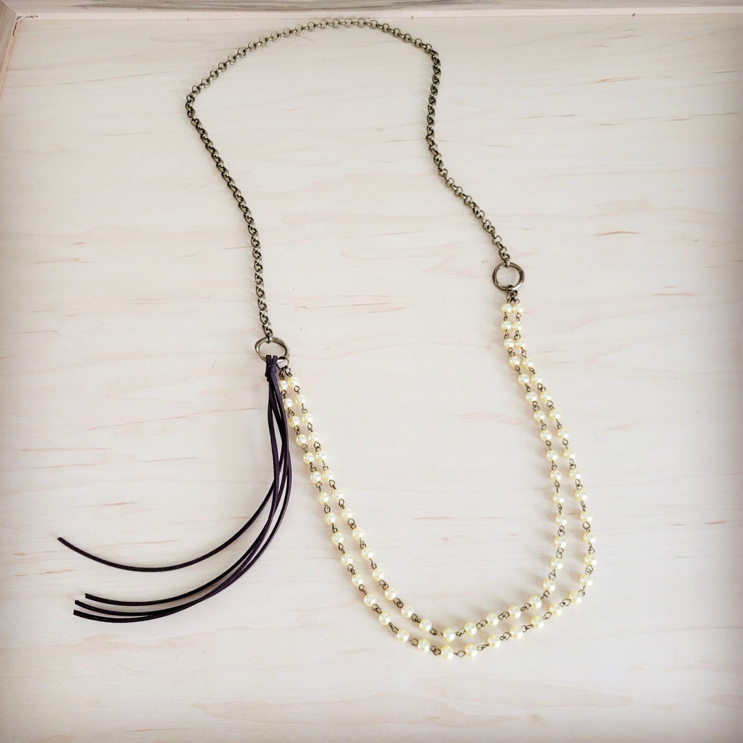 Champagne pearl beaded double-strand necklace with black leather tassel and gold-tone chain.