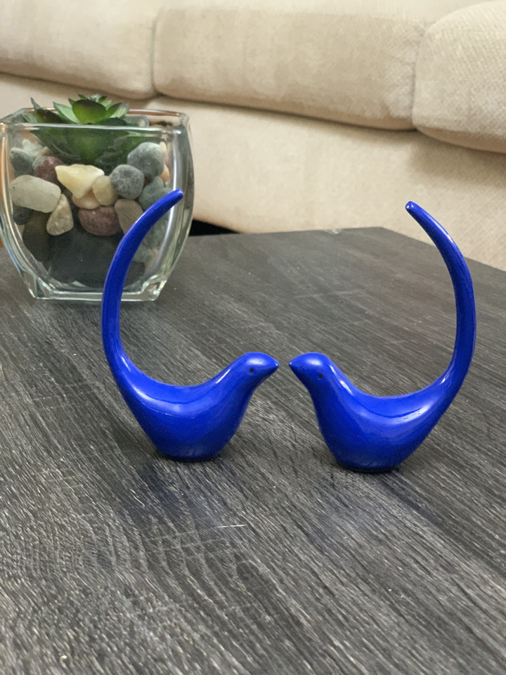 Blue bird figurine pair with glass jar of decorative stones beside them