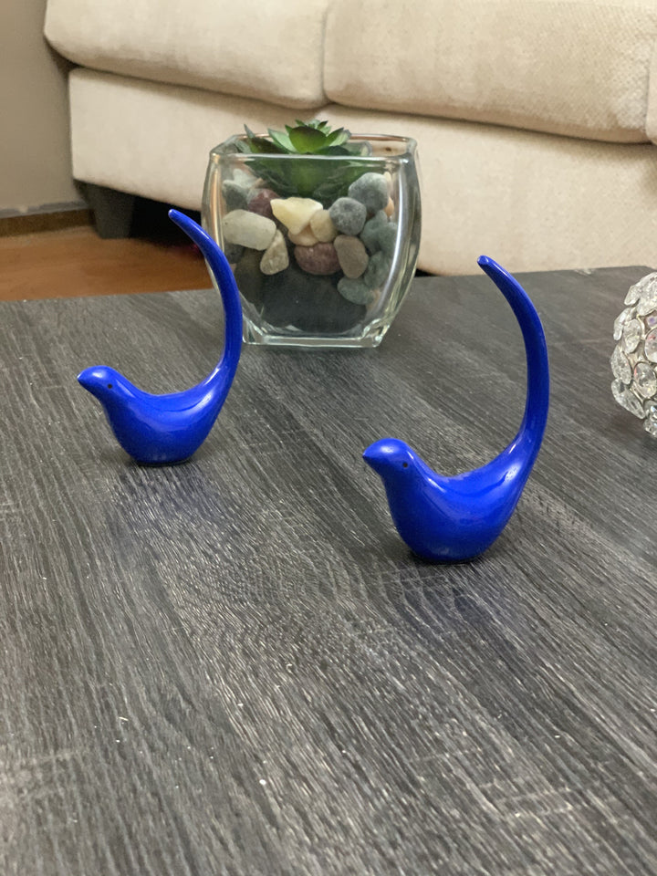 Blue bird figurine pair with glass jar and decorative stones on a tabletop