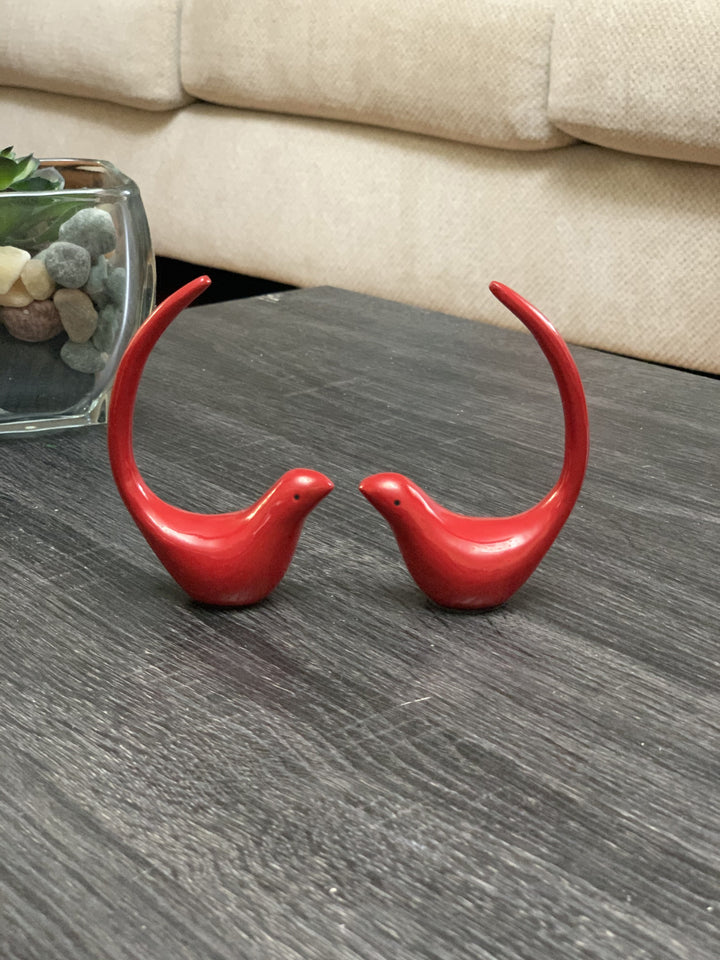 Red bird figurine pair with curved wings, glossy finish on tabletop