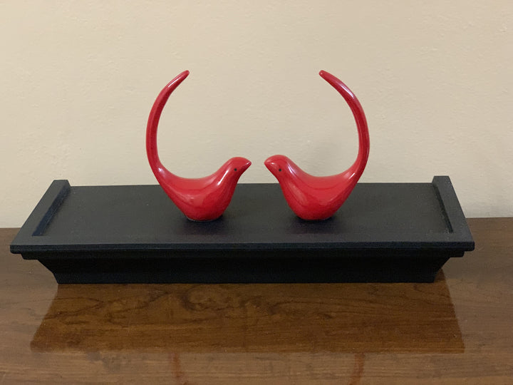 Red bird figurine pair displayed on black base, glossy red
