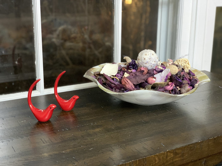 Red bird figurine pair on tabletop beside decorative bowl, glossy red