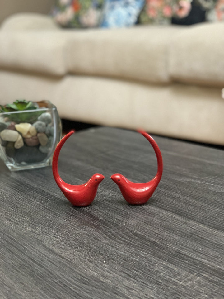 Red bird figurine pair on gray shelf, glossy red bird shapes