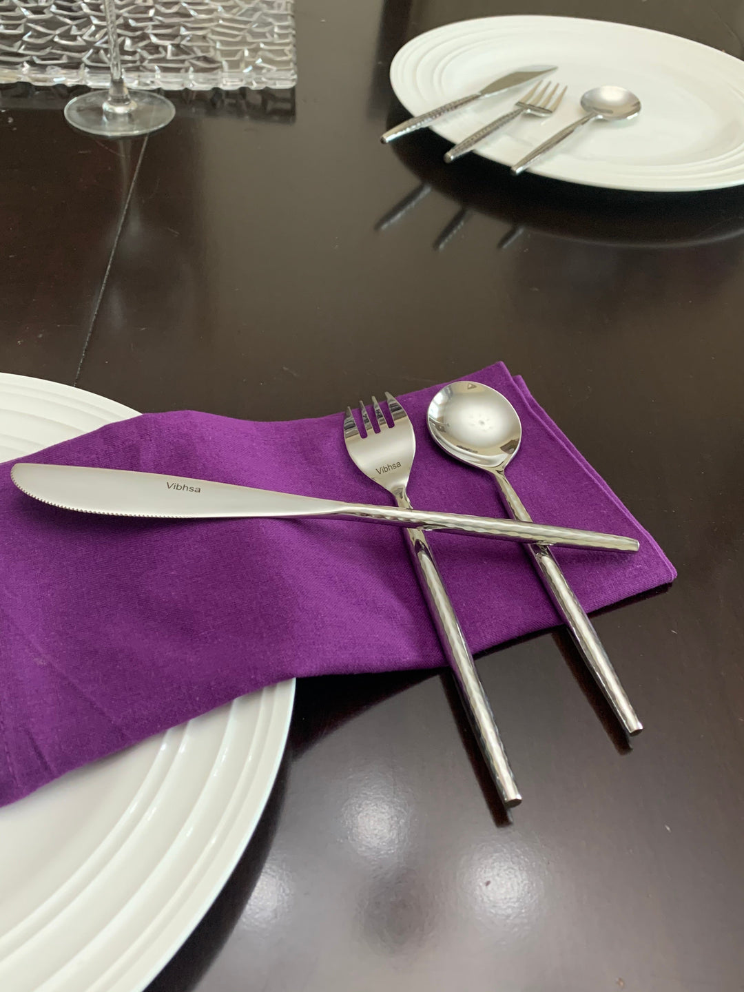 Vibhsa silverware set: knife, fork, and spoon on a folded napkin and plates