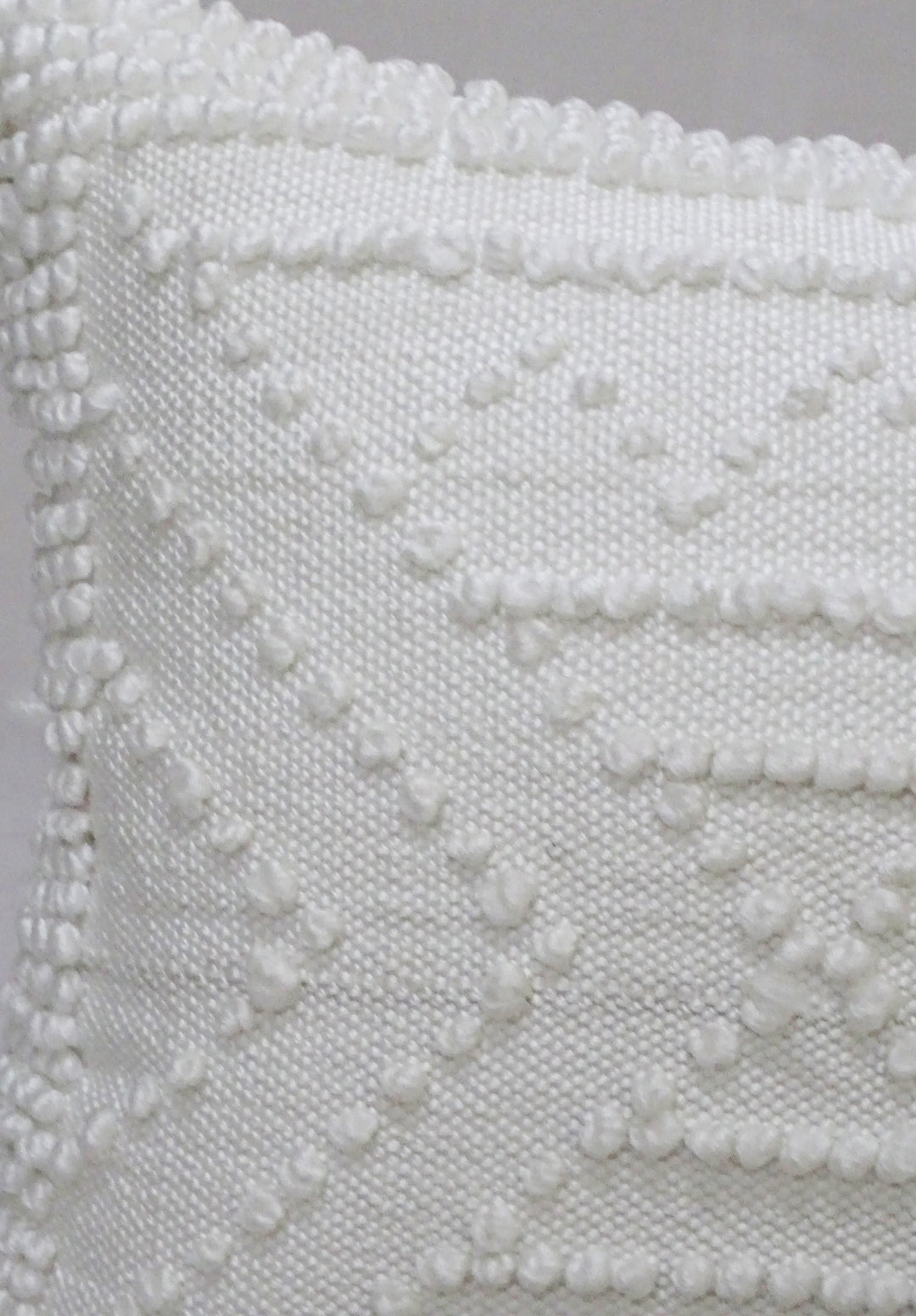 White textured outdoor pillow cover close-up with raised diamond and wave pattern