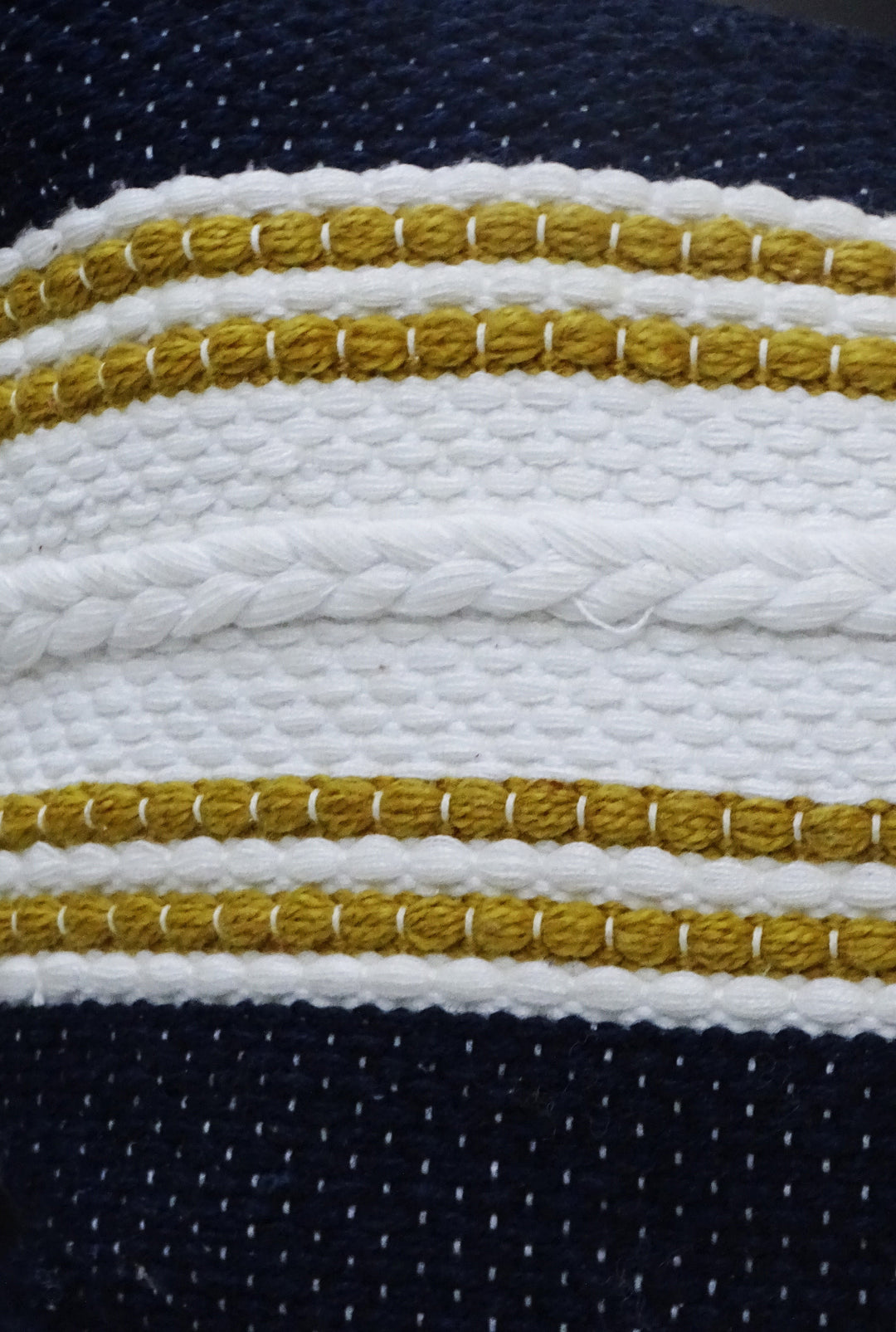 Striped pillow close-up: braided gold trim on navy and white fabric