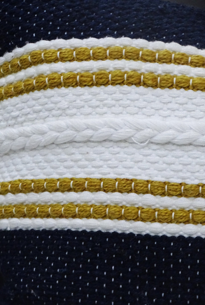 Striped pillow close-up: braided gold trim on navy and white fabric
