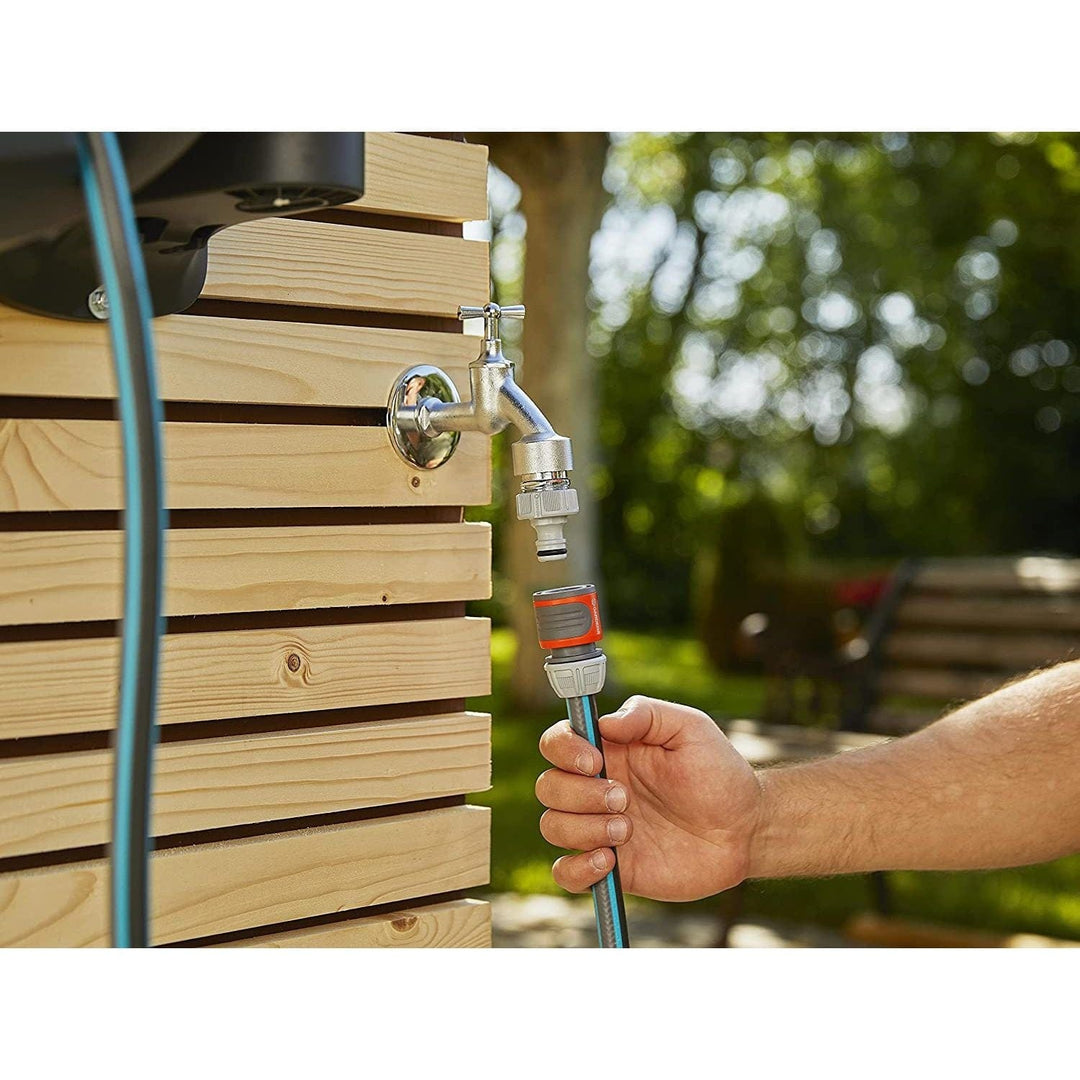 Hand connecting a hose to a wall-mounted reel using a quick connector fitting