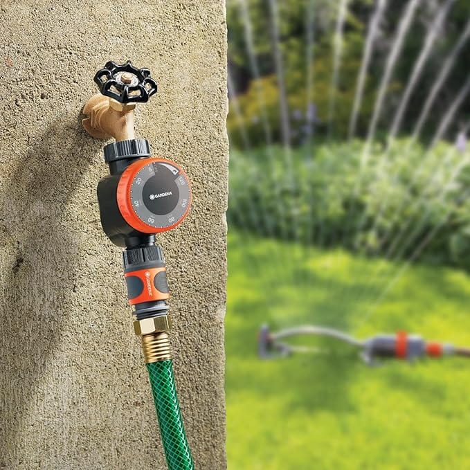 Water timer with flow-control dial mounted to wall, connected hose and spray