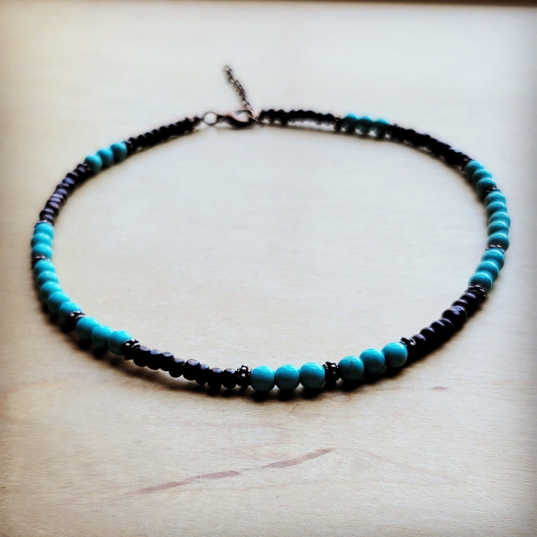 Turquoise blue bead collar necklace with dark beads and copper-tone chain, close-up.