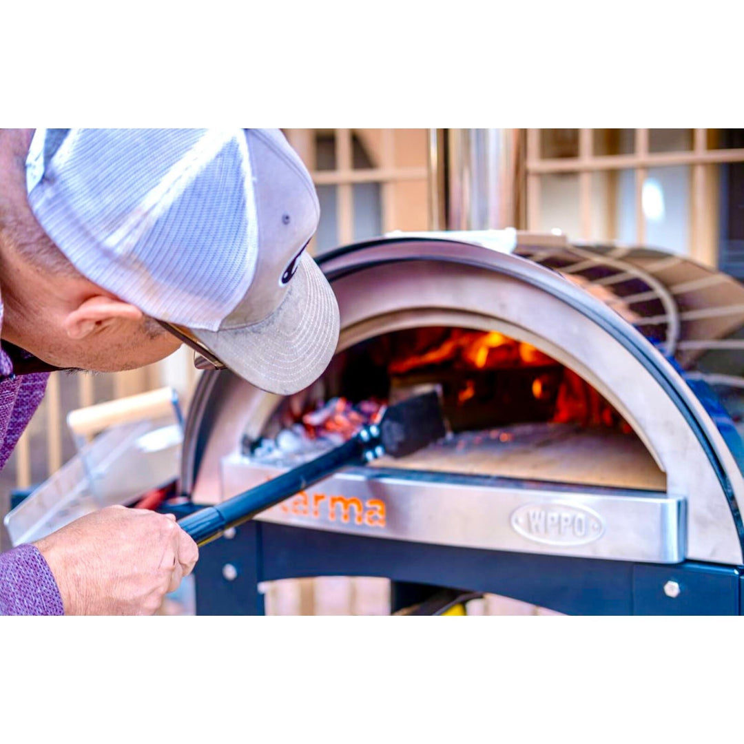 Blue-handled coal rake lifting coals inside a wood-fired oven