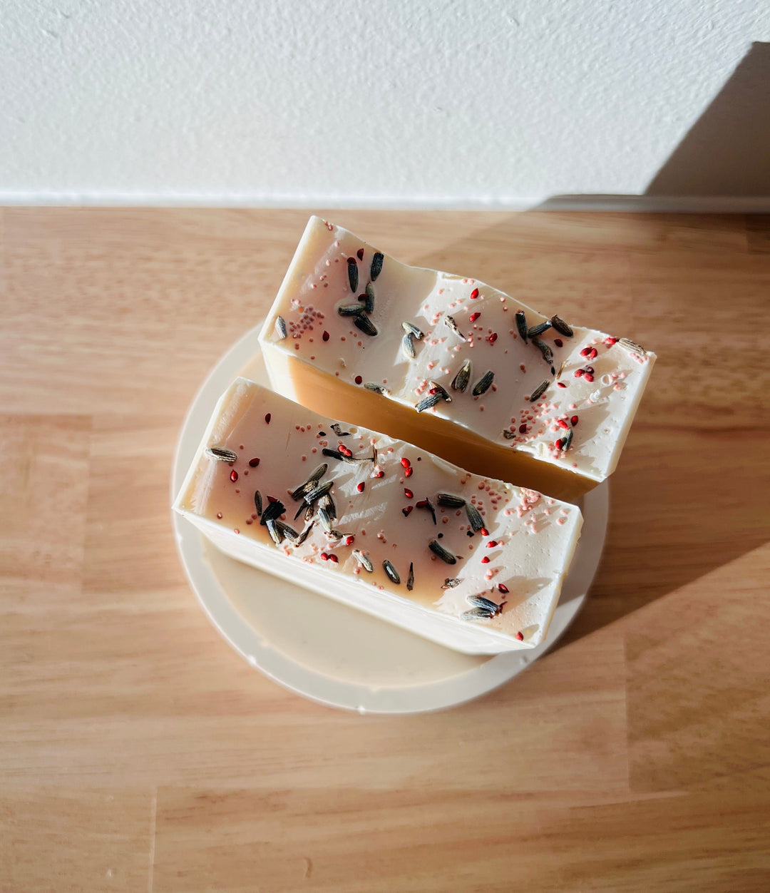 Handmade soap bars, off-white with dark speckles and red herb flakes