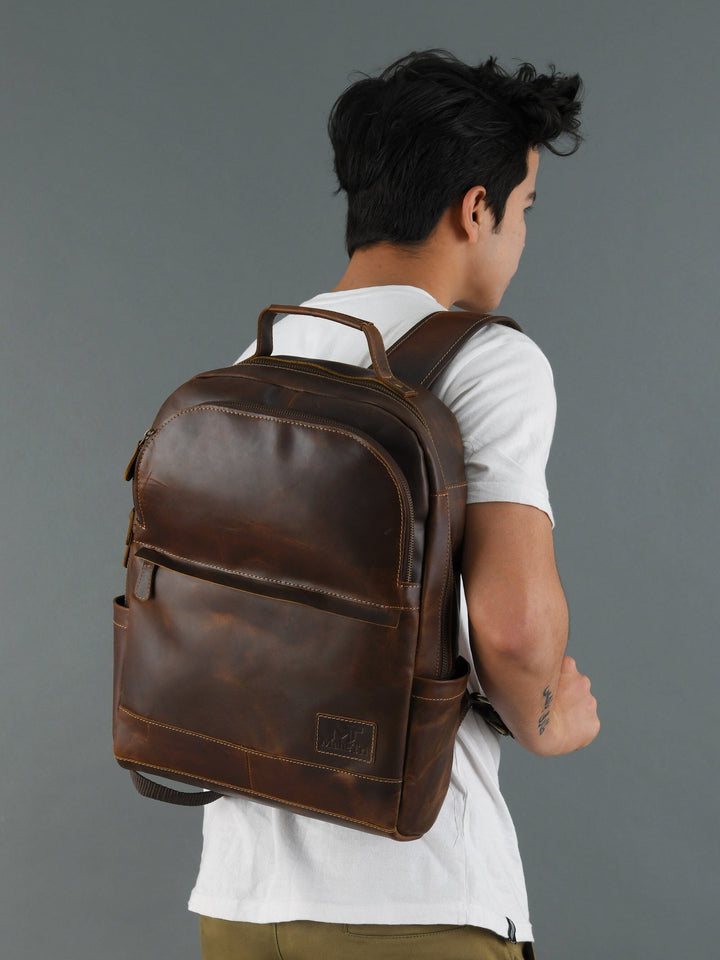 Brown buffalo leather backpack worn by model; back panel and adjustable shoulder straps.