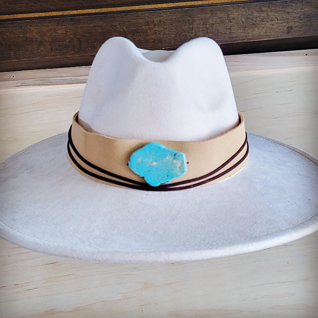 White wide-brim suede hat with tan band, turquoise concho, and double dark trim