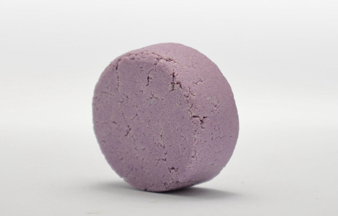 Lavender-purple round shampoo bar with textured surface