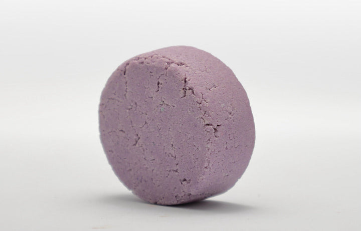 Lavender-purple round shampoo bar with textured surface