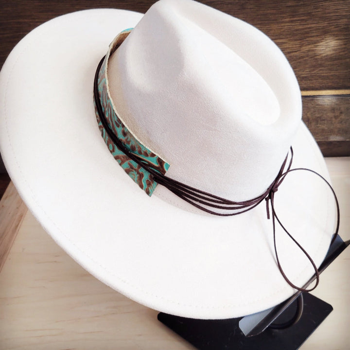 White cowboy hat shown at an angle with turquoise patterned leather hat band and long tie strings