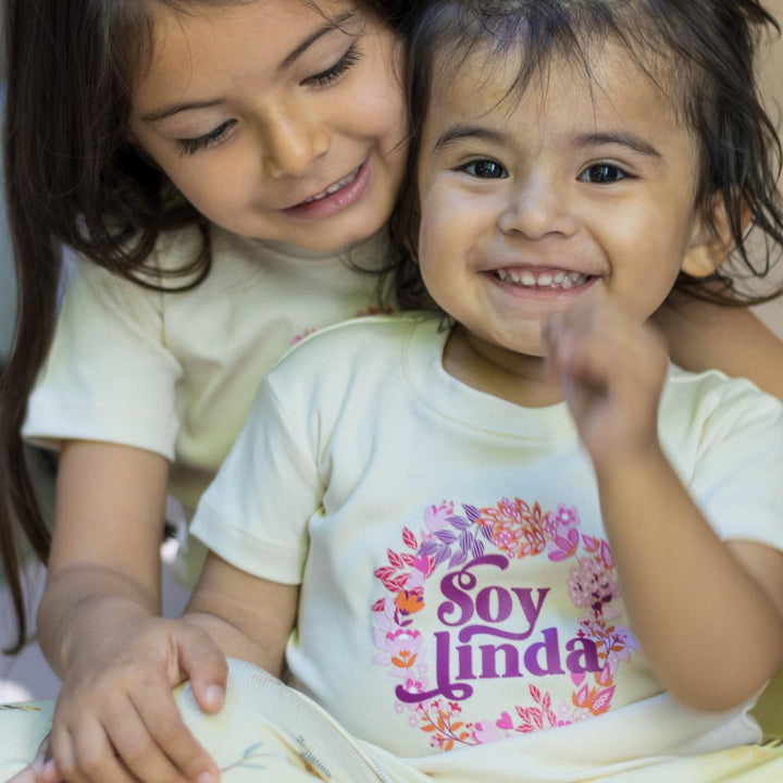 White organic cotton tees on children with floral “Soy linda” logo print