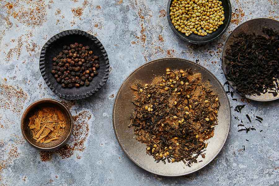 Spice rub blend with dried herb flakes in a metal bowl and small bowls