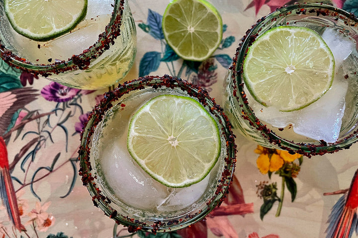 Chili-lime rim seasoning on cocktail glasses with lime slices and ice