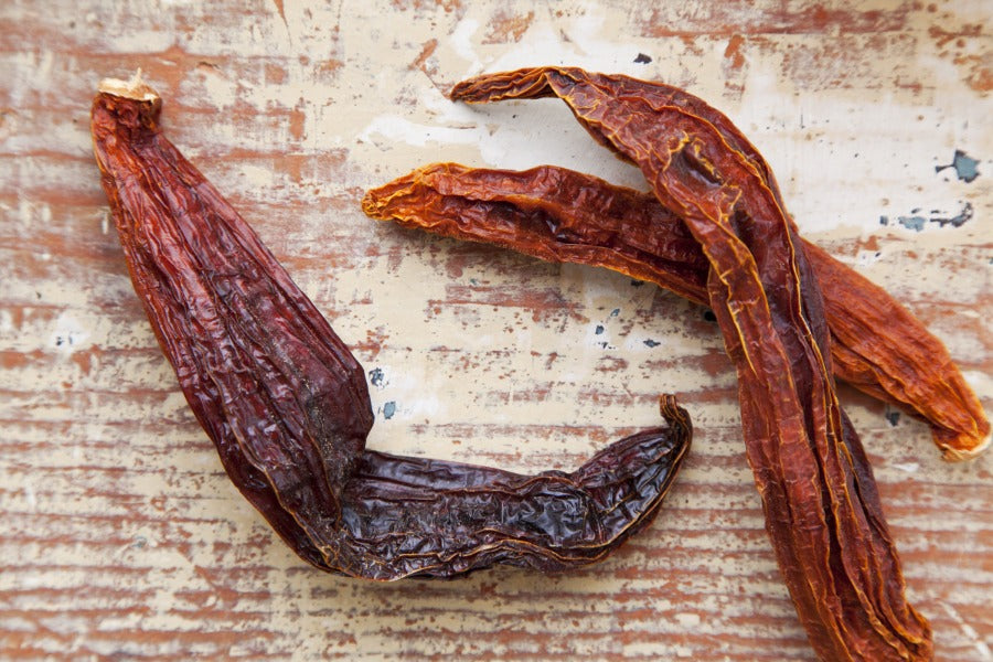 Aji Mirasol dried chile pods, dark reddish-brown pods on a surface