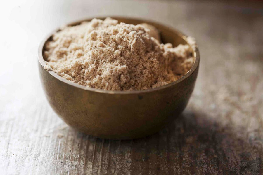 Amchoor mango powder in a round metal bowl, light beige fine powder