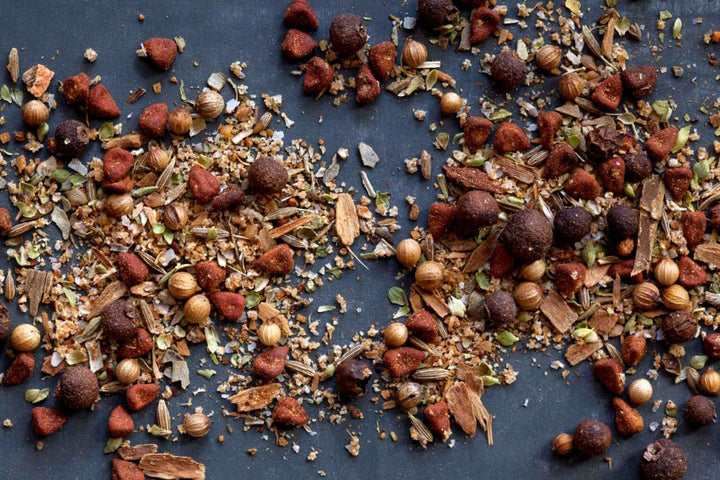 BBQ rub spice blend with red-brown granules and herbs scattered on a dark surface