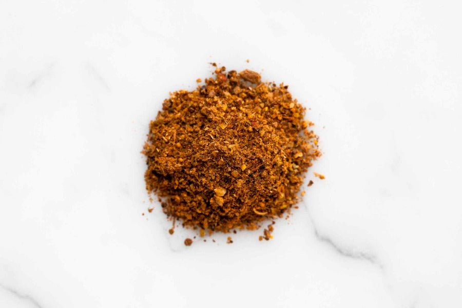 BBQ rub mound of finely ground red-brown seasoning on a white background