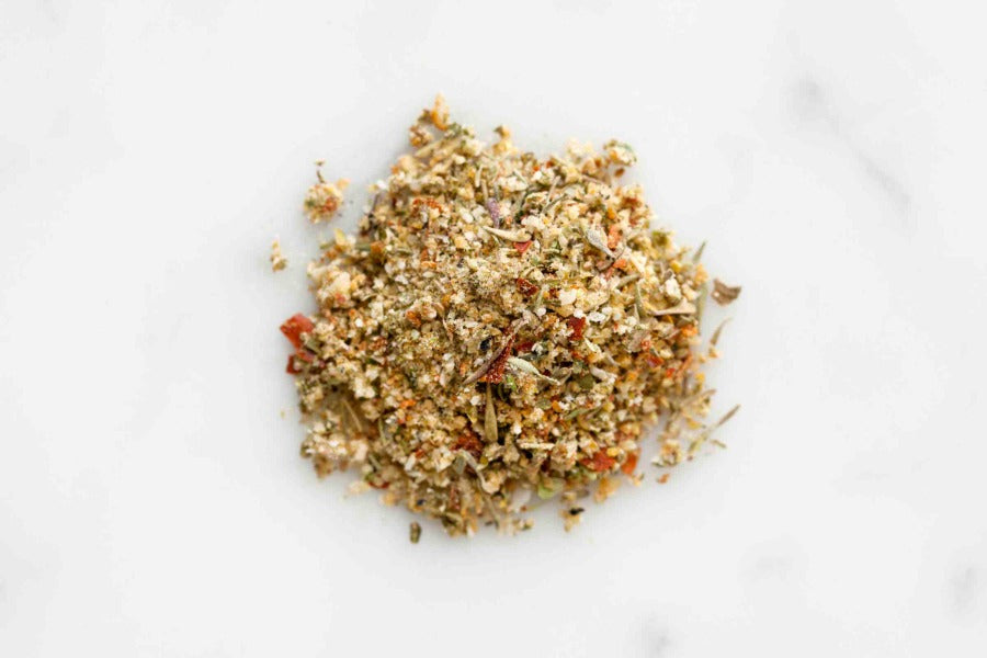 Ground citrus rub seasoning mound with mixed spices on white surface