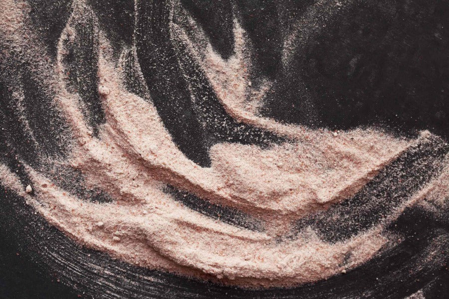 Black salt granules with dark and light speckled texture in a swirl mound