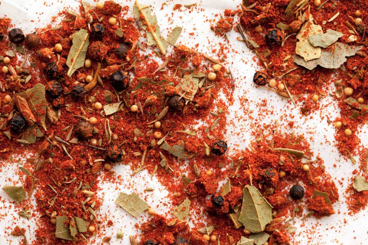 Cajun spice blend seasoning, red-orange flakes and herbs with bay leaf pieces