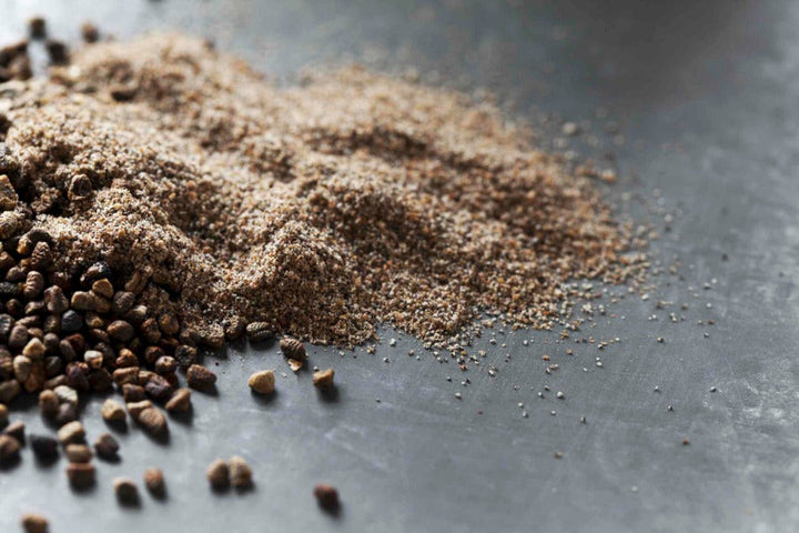 Ground cardamom powder, light brown spice dust spread on a surface