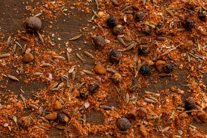 Caribbean spice blend, orange-brown ground spices with seeds and herbs in a heap
